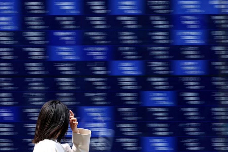 A woman walks past an electronic screen displaying stock quotation board in Tokyo, Japan April 15, 2025.