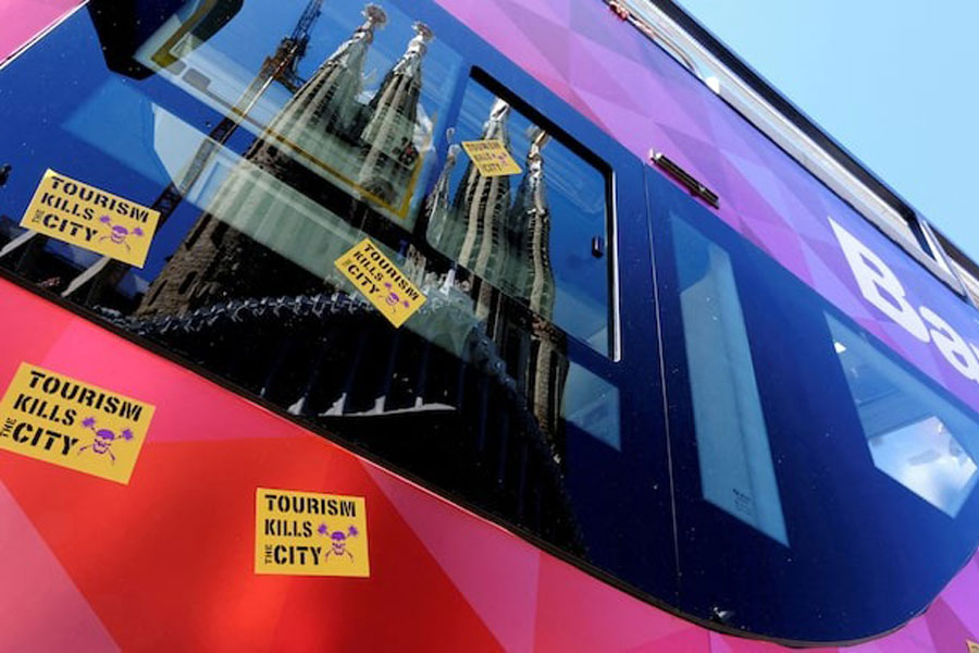Stickers that read "Tourism kills the City" are stuck on a Tourist City Sightseeing bus, with the La Sagrada Familia Basilica reflected on it, during a protest against mass tourism in Barcelona, Spain April 27, 2025.