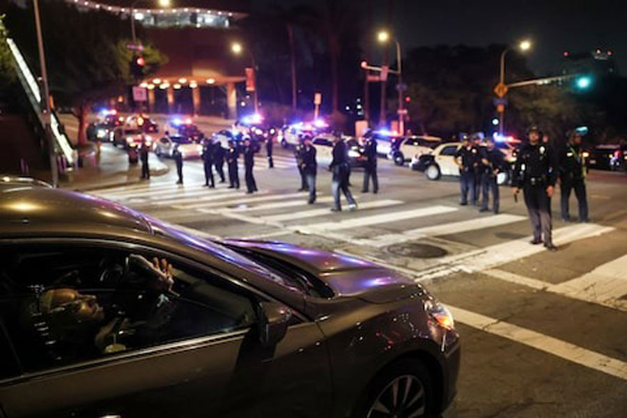 A man in a car uses his mobile phone as members of law enfocement stand guard on a road after curfew, as protests against federal immigration sweeps continue, in downtown Los Angeles, California, US June 10, 2025.