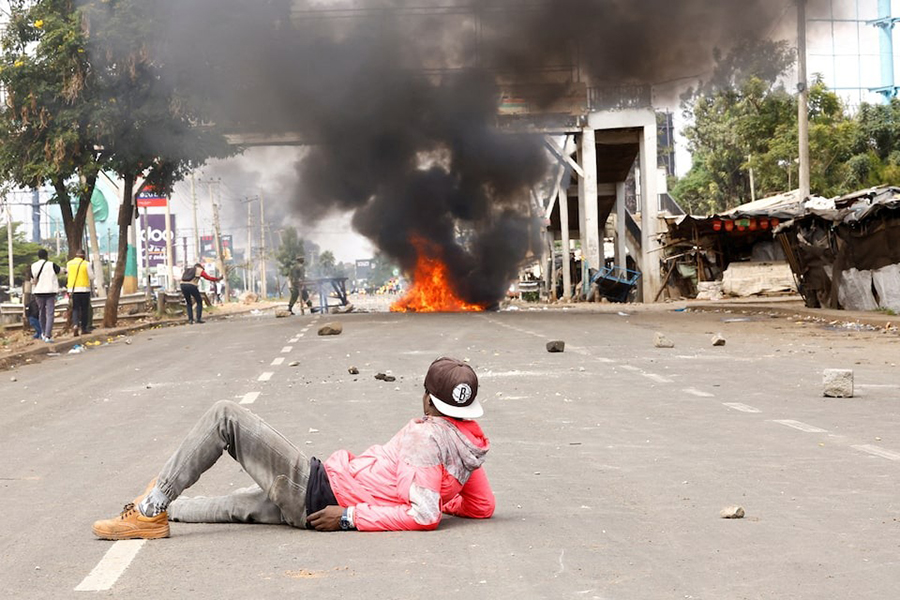 A demonstrator lies on the road, watching clashes with police as a fire burns, at the "Saba Saba People's March" anti-government protest in Nairobi, Kenya on July 7 — Reuters photo
