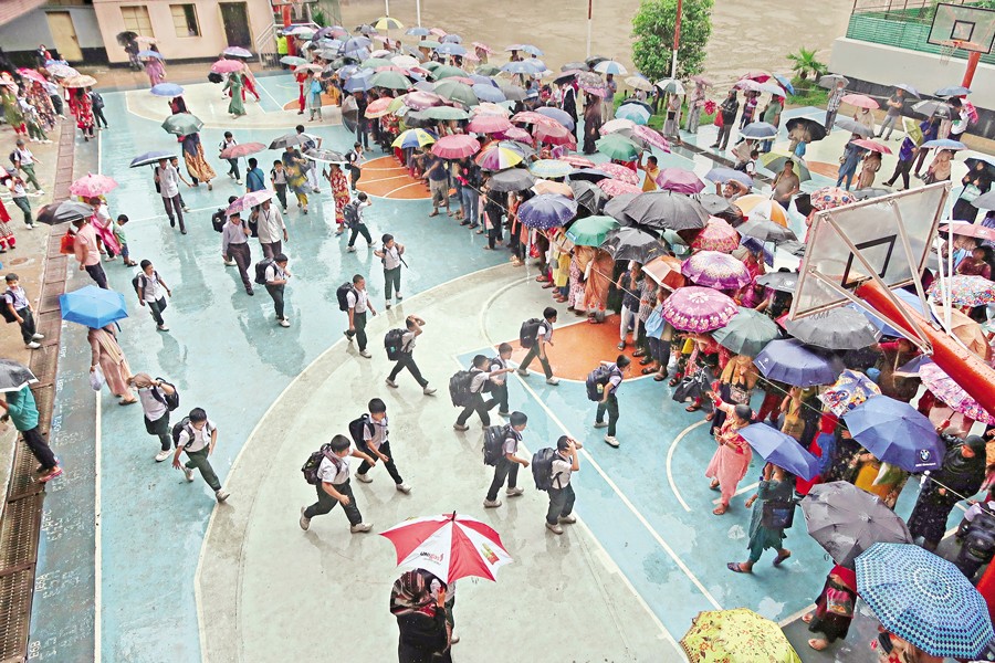 Parents holding umbrellas wait for their children on the premises of St. Gregory's High School and College in Dhaka on Wednesday. The capital city has been experiencing moderate to heavy rain over the last couple of days, disrupting normal life. — FE Photo by Shafiqul Alam