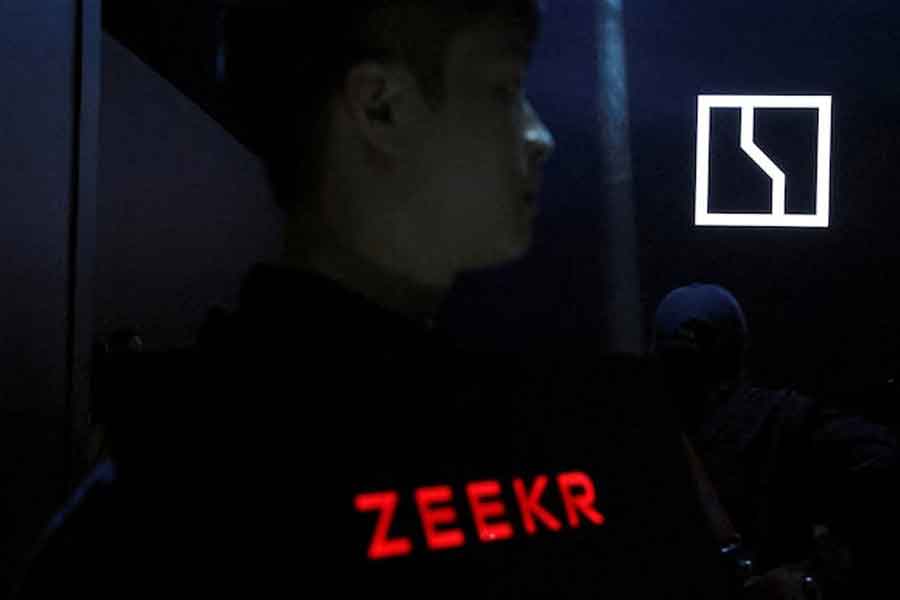 A staff member holds a Zeekr sign to guide attendants arriving at a Zeekr event launching the EV maker's G-Pilot smart driving solution, in Hangzhou, Zhejiang province, China March 18, 2025.