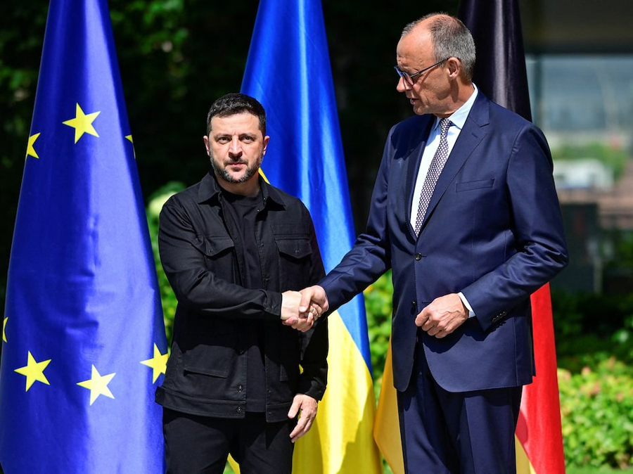 Ukrainian President Volodymyr Zelensky (L) is welcomed by German Chancellor Friedrich Merz upon arrival in the garden of the chancellery in Berlin to join a video conference of European leaders with the US President on the Ukraine war ahead of the summit between the US and Russian leaders, on August 13, 2025. European leaders will hold online talks with US President Donald Trump, hoping to convince him to respect Ukraine’s interests when he discusses the war with Putin in Alaska on Friday.