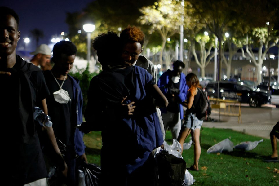 A couple of sub-saharan migrants embrace in a public park after arriving from Algeria earlier in the day, as more than 30 boats carrying about 600 irregular migrants have reached the Balearic Islands since Monday, according to officials, in Palma de Mallorca, Spain, August 12, 2025.