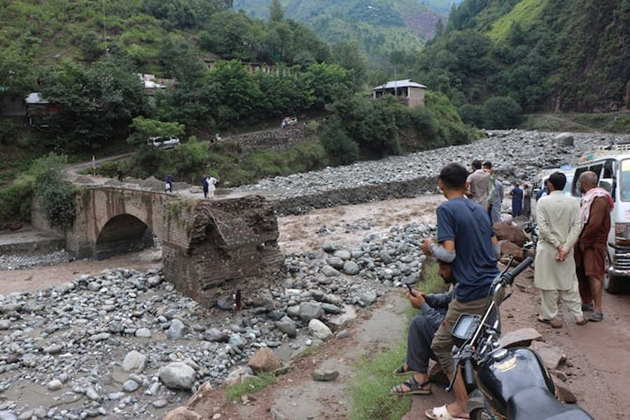 Residents gather at the site of a damaged bridge following a storm that caused heavy rains and flooding on the outskirts of Muzaffarabad, the capital of Pakistan-administered Kashmir, August 15, 2025.