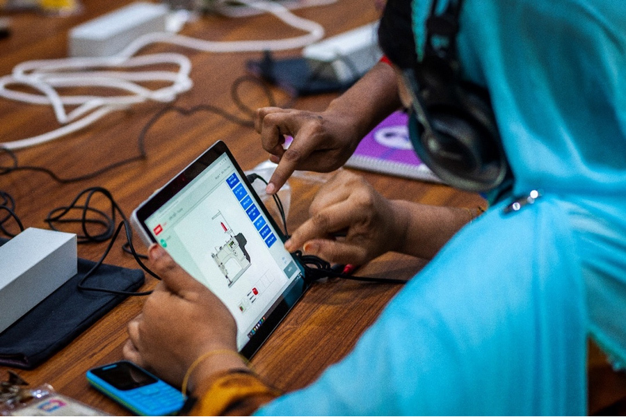 A woman worker is learning to use tab to operate sophisticated sewing machine at a textile factory in Dhaka —AF Photo