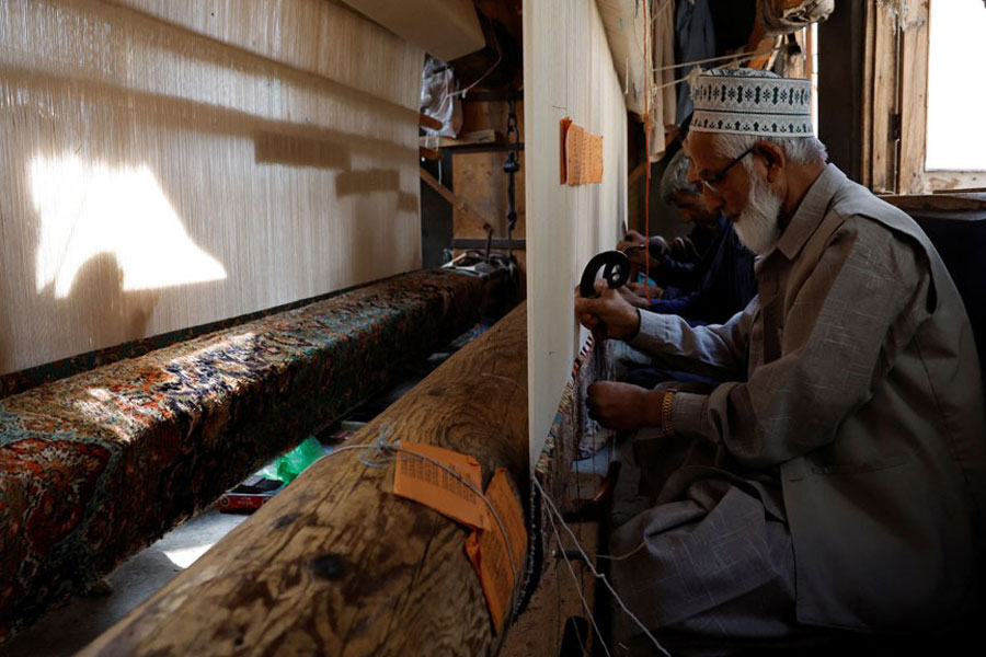 Ghulam Qadir, 75, an artisan, weaves a Kashmiri hand-knotted carpet along with other artisans inside a workshop in Srinagar, Indian Kashmir, Oct 4, 2025.