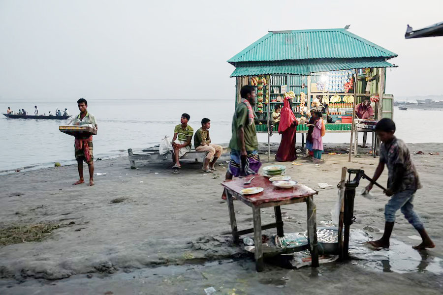 People sit near a shop on the bank of the Brahmaputra River. The World Bank estimates one in every seven Bangladeshis could be displaced by climate-related disasters by 2050 —REUTERS