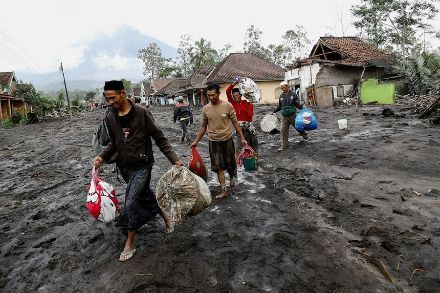 Local residents carry valuable goods from their houses in an area affected by an overnight Mount Semeru volcano eruption, in Supiturang village, Lumajang, East Java province, Indonesia on November 20, 2025 — Retuers photo