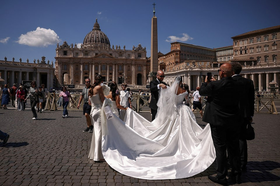A groom arranges the wedding dress of the bride during their wedding photo session on St. Peter’s Square at the Vatican on April 29, 2025 — Reuters/File