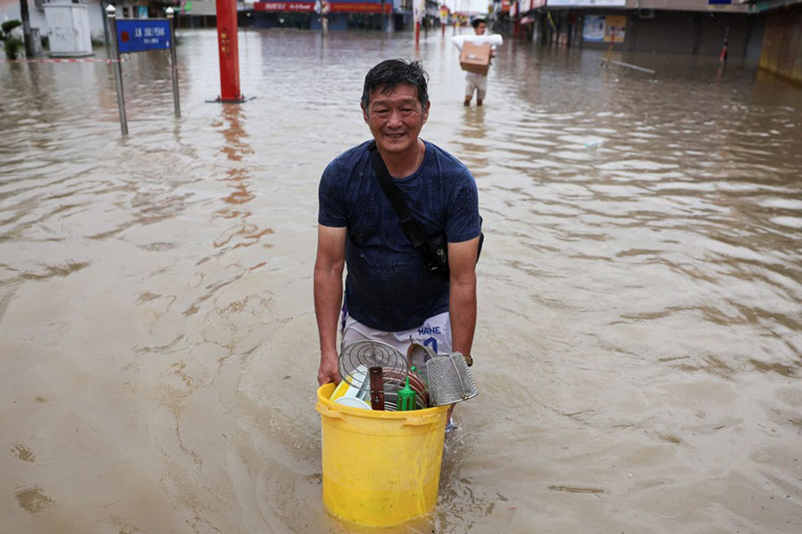Men wade through floodwater carrying their belongings after heavy rain in the northern states of Malaysia, bordering Thailand, in Kangar, Malaysia, Nov 26, 2025.