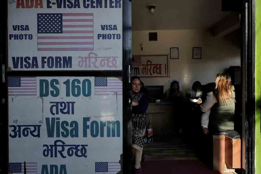 A woman holding a child waits to fill out a U.S. visa application form at a consultancy that assists with visa paperwork in Kathmandu, Nepal, November 28, 2025.