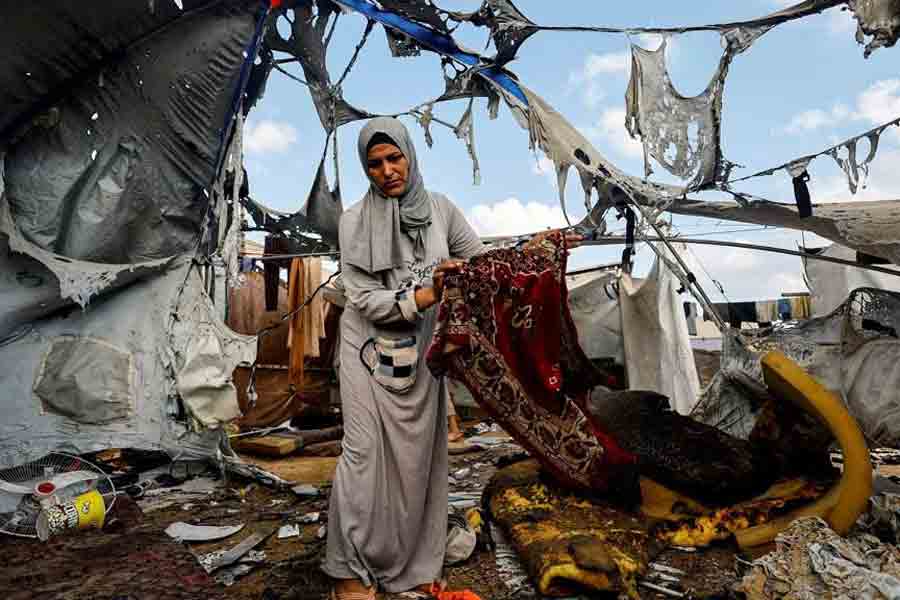 A Palestinian woman carries a prayer mat at the site of an overnight Israeli strike on a tent, in Gaza City, Sept 8, 2025.