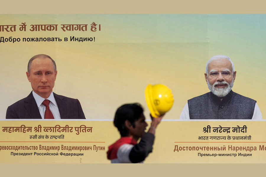 A worker walks past a hoarding with images of Russian President Vladimir Putin and Indian Prime Minister Narendra Modi ahead of Putin's visit, in New Delhi, India, Dec 4, 2025.