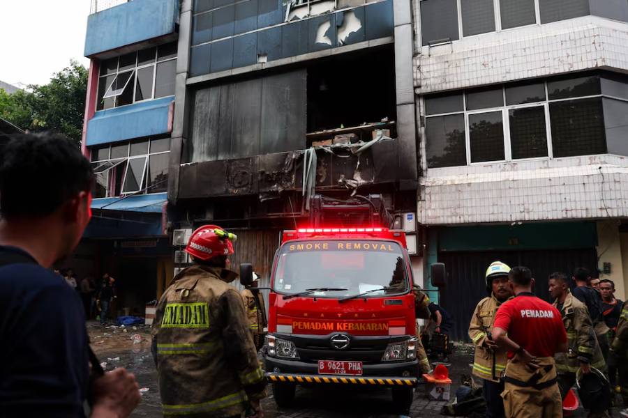Firefighters stand near a seven-storey building damaged by fire, in Jakarta, Indonesia, December 9, 2025.