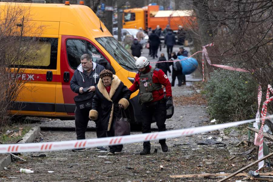 A medic assists a resident as she leaves her apartment building that was hit by a Russian drone, amid Russia's attack on Ukraine, in Kyiv, Ukraine December 23, 2025.