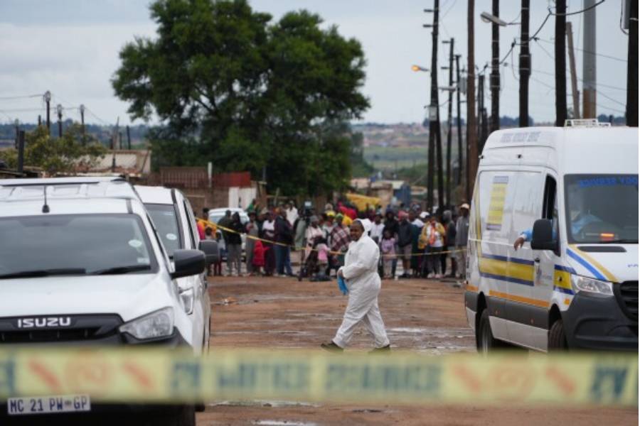 Onlookers gather at the scene of a mass shooting where gunmen killed nine and injured at least 10 in a pub in Bekkersdal, South Africa, Sunday, Dec. 21, 2025.