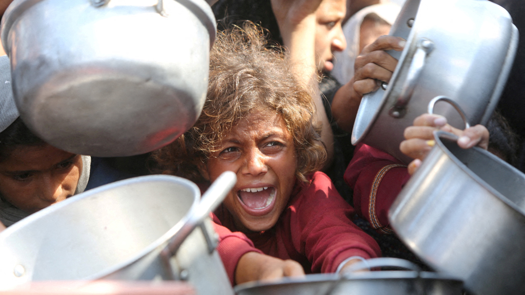 A child reacts surrounded by pots as Palestinians wait to receive food from a charity kitchen in Khan Younis, southern Gaza Strip, Aug 21, 2025. REUTERS/Hatem Khaled