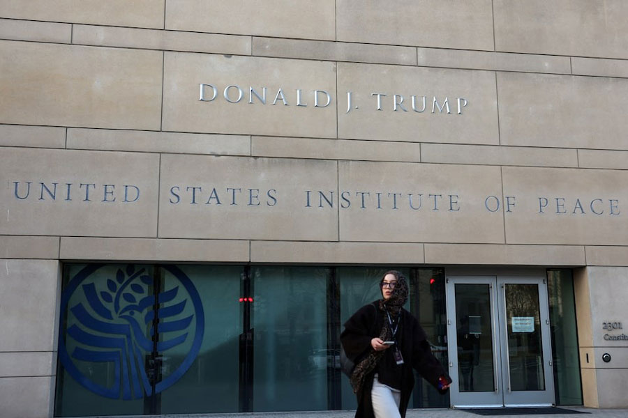 A woman walks past the newly named Donald J Trump US Institute of Peace on the day US President Donald Trump, President of the Democratic Republic of the Congo Felix Tshisekedi and President of Rwanda Paul Kagame take part in a signing ceremony, in Washington, DC, US, December 4, 2025.