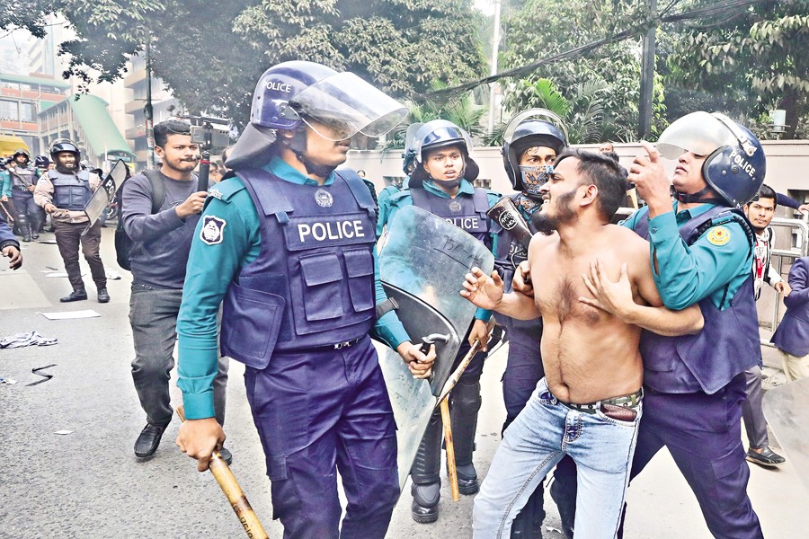 Police take away a mobile phone trader at Karwan Bazar intersection from a sit-in after a baton charge to disperse them on Sunday. The protesters demanded the withdrawal and postponement of the National Equipment Identity Register (NEIR) system — FE photo