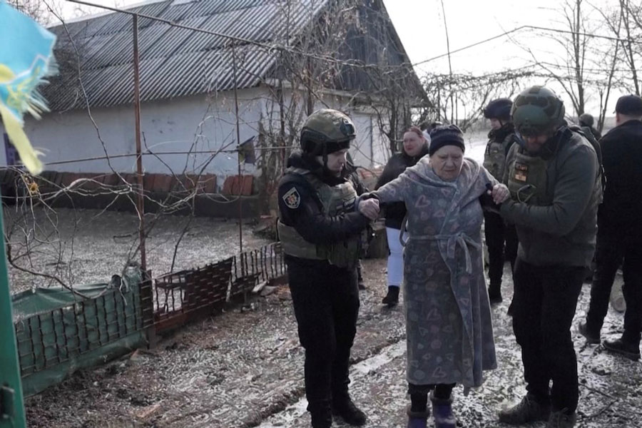 Ukrainian national police officers assist a woman during an evacuation of residents from the Tavriiske and Yurkivka villages in Ukraine's Zaporizhzhia region, amid Russia's attack on Ukraine, in this screengrab from a video, February 3, 2026.