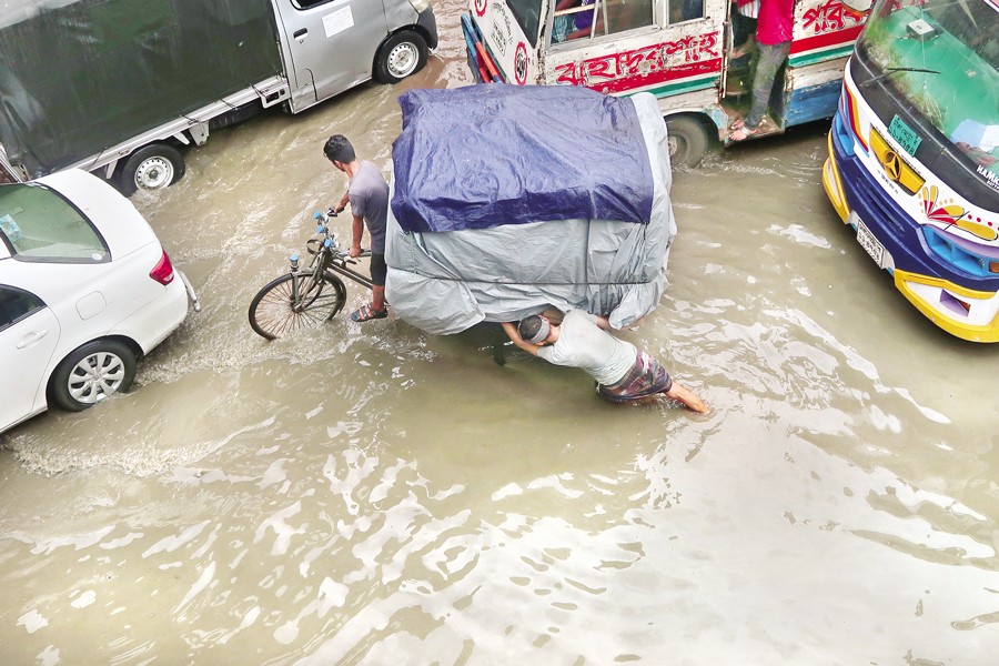 Many city streets like this one at Dayaganj go under water following a downpour on Friday, leading to inconveniences for commuters and pedestrians. — FE photo by Shafiqul Alam