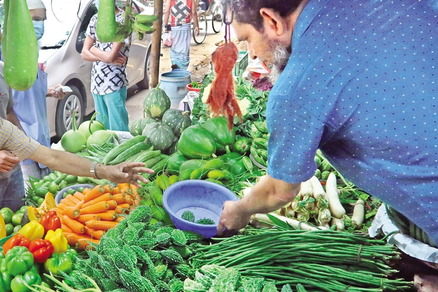 A vendor sells vegetables at a kitchen market located in the AGB Colony within Motijheel area of the city on Sunday. Spiralling vegetable prices have compelled consumers to purchase in smaller quantities. In this photo, a man is seen buying just two or three pieces of bitter gourd. — FE photo by Shafiqul Alam