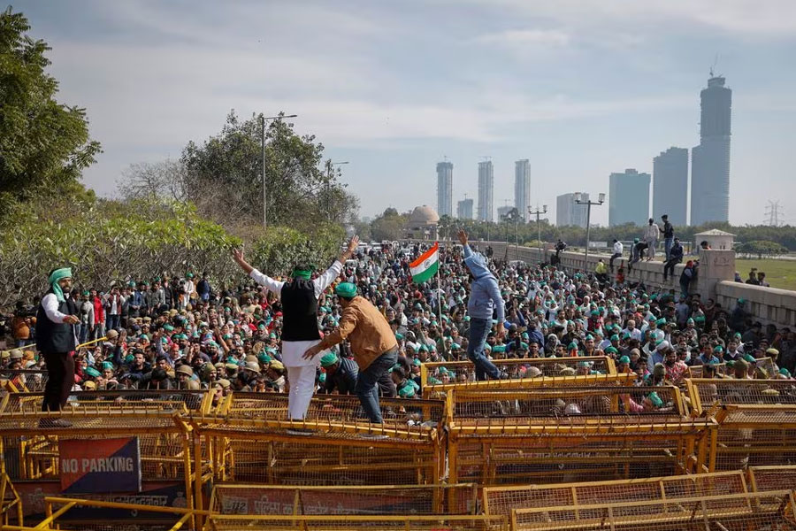 Farmers climb a police barricade during a protest demanding a hike in land compensation and better rehabilitation facilities for their families, in Noida on the outskirts of New Delhi, India, February 8, 2024.