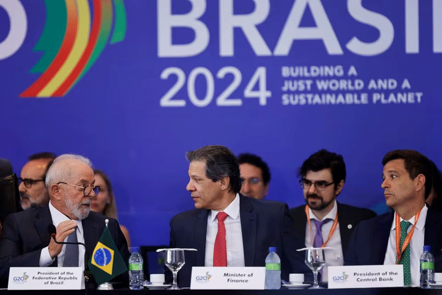 Brazil's President Luiz Inacio Lula da Silva speaks to Brazil's Finance Minister Fernando Haddad as Brazil's Central Bank President Roberto Campos Neto looks on during the meeting of the opening of the G20 sherpa and finance tracks joint session in Brasilia at the Itamaraty Palace in Brasilia, Brazil December 13, 2023.