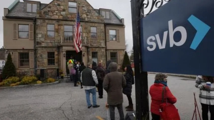 Customers wait in line outside a branch of the Silicon Valley Bank in Wellesley, Massachusetts, US, March 13, 2023.
