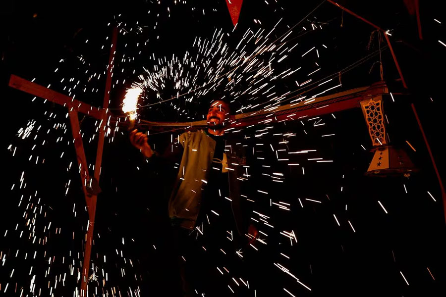 A man waves a homemade sparkler firework as displaced Palestinians prepare their tents for Ramadan, amid the ongoing conflict between Israel and the Palestinian Islamist group Hamas, in Rafah, in the southern Gaza Strip March 9, 2024.