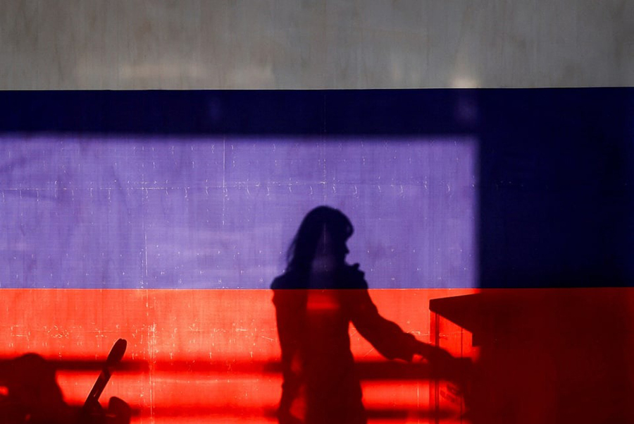 A woman is silhouetted behind a banner in the colours of the Russian flag at a polling station during the Russian presidential election in the settlement of Gorki Leninskie in the Moscow Region, Russia on March 15, 2024 — Reuters photo
