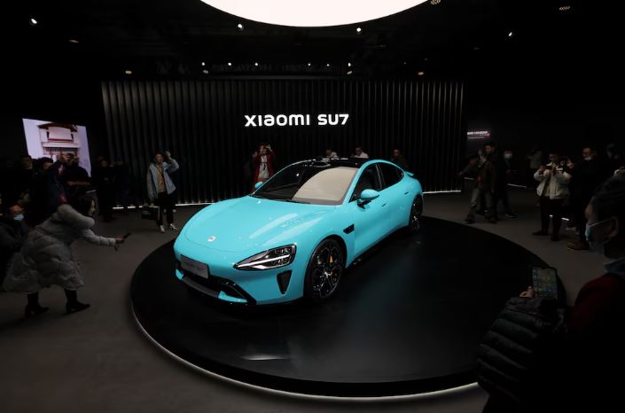 Visitors film around Xiaomi's first electric vehicle, the SU7, displayed at an event in Beijing, China December 28, 2023. REUTERS/Florence Lo/File Photo