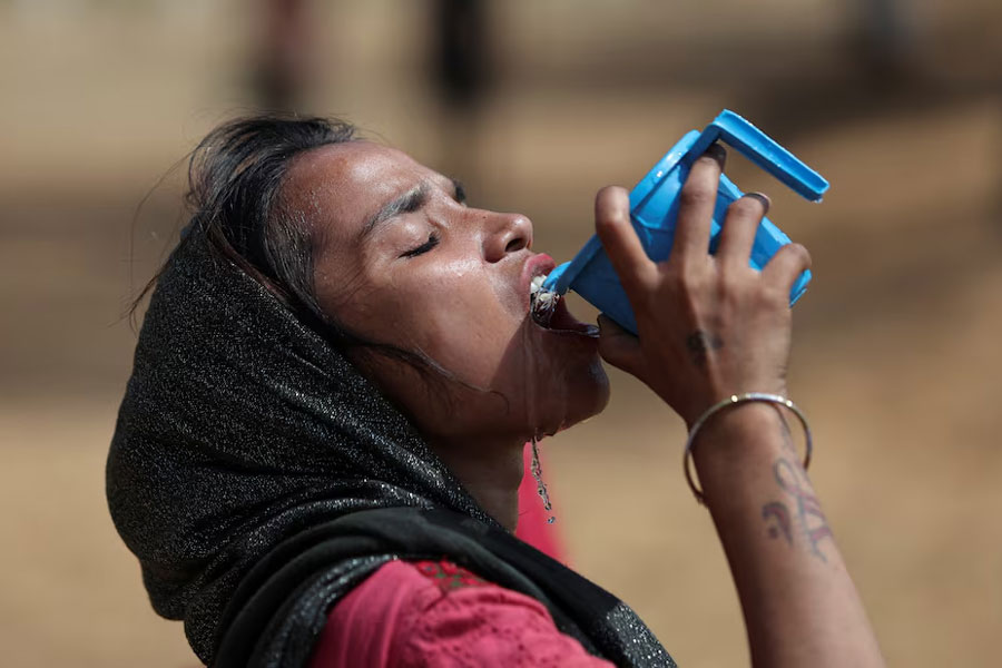 A woman drinks water from a mug on a hot summer day in New Delhi, India June 9, 2023.