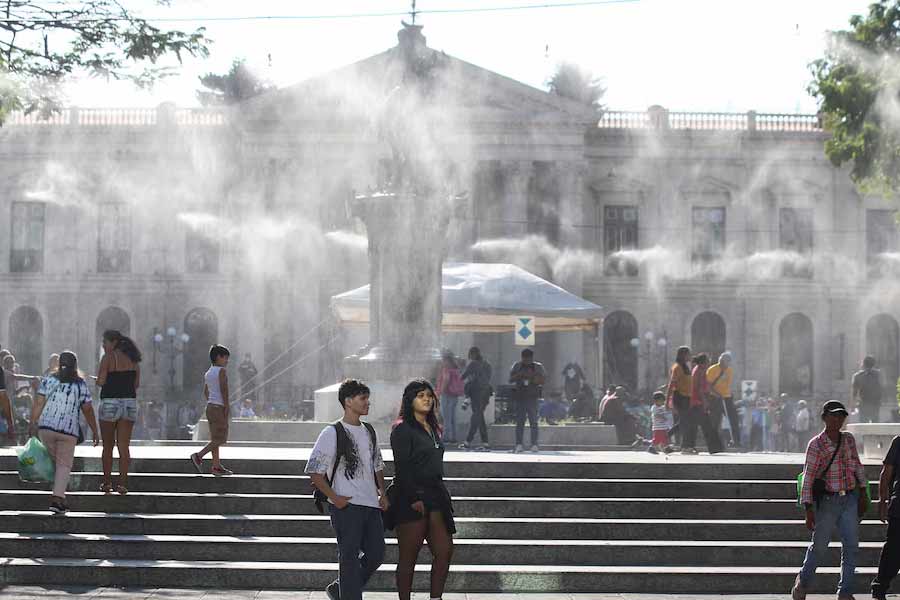 People walking as water is sprayed by a system to alleviate the high temperatures caused by a heat wave, at the Gerardo Barrios square, in San Salvador, El Salvador, recently -Reuters file photo