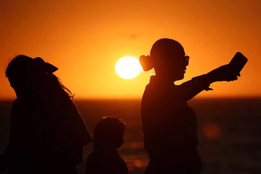 People are silhouetted at sunset as they visit the Malecon, one day ahead of a total solar eclipse in Mazatlan, Mexico April 7, 2024.