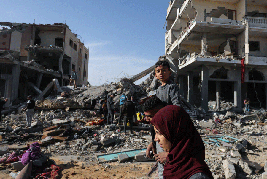 Displaced Palestinians return to their homes as they walk near houses destroyed in an Israeli strike during the conflict, amid the temporary truce between Hamas and Israel, in Khan Younis in the southern Gaza Strip November 24, 2023.