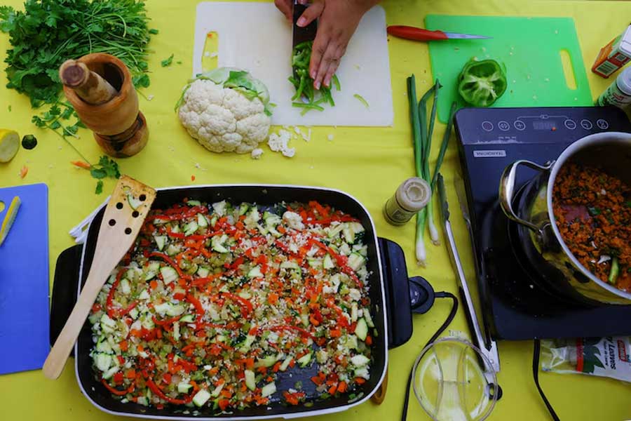 A patient adds green peppers to a dish called “Cauliflower Chicken Vegetable Paella Confusi@n Latina,” as part of a healthy weight clinic teaching children and their families healthier eating habits, at the Holyoke Health Center in Holyoke, Massachusettss, U.S., June 11, 2024.