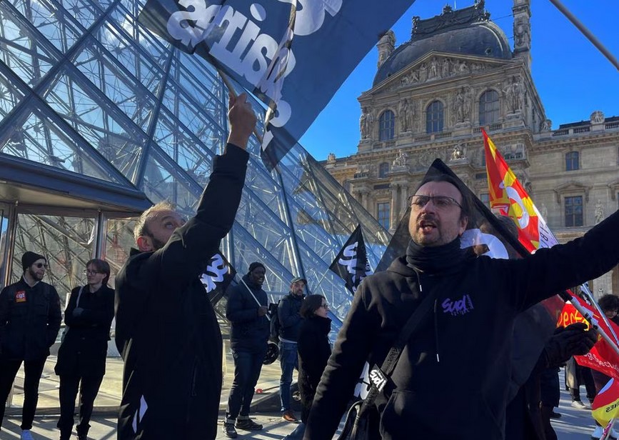 Protesters holding French CGT and Sud Culture Solidaires labour unions flags stand in front of the glass Pyramid to block the entrance of the Louvre museum to protest against the French government's pension reform, in Paris, France, France, March 27, 2023. REUTERS/Marco Trujillo