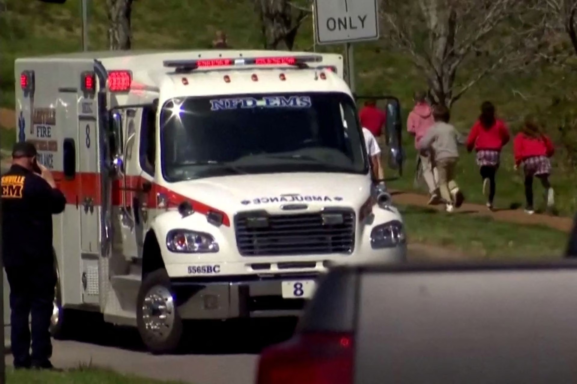 Children run past an ambulance near The Covenant School after a shooting in Nashville, Tennessee, US on, March 27, 2023 in a still image from video — WKRN/NewsNation via REUTERS