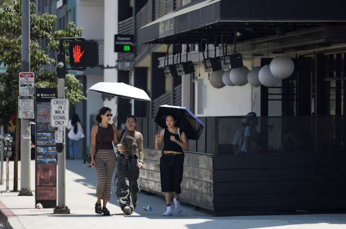 People hold an umbrella to protect themselves from the sun in Little Tokyo during hot weather in Los Angeles, California, U.S. July 5, 2024. REUTERS/Etienne Laurent/File Photo