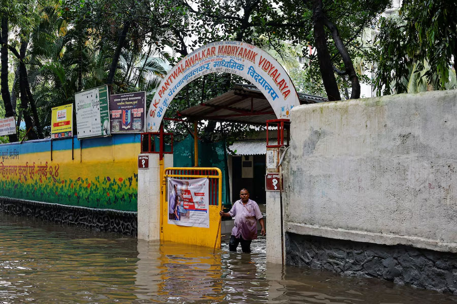 A man stands at the entrance of a school on a waterlogged street after heavy rains in Mumbai, India, July 8, 2024.
