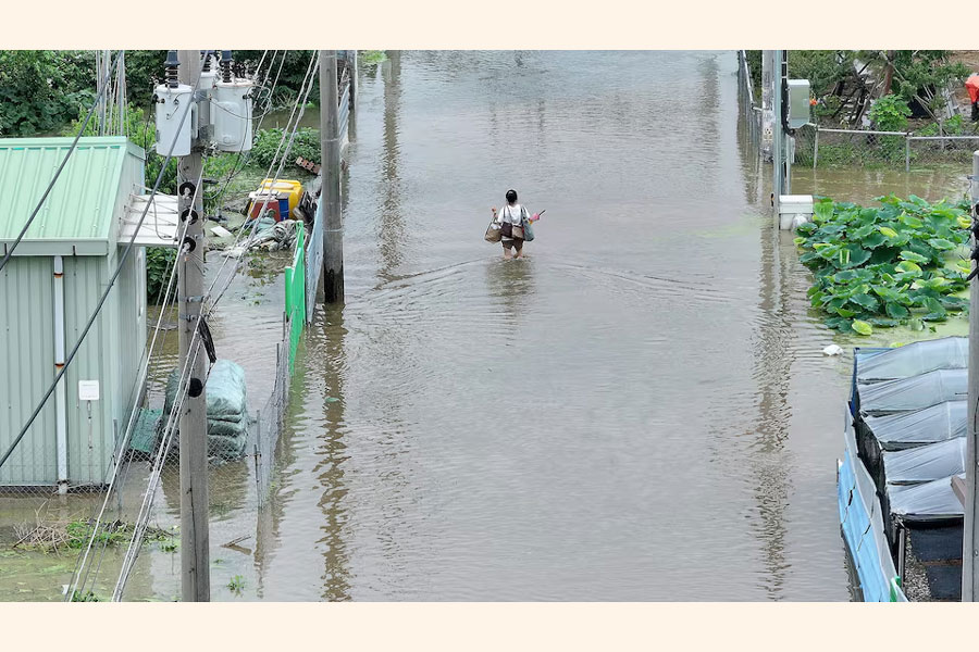 A woman carrying belongings makes her way through a flooded street due to heavy rain in Daegu, South Korea, July 10, 2024.