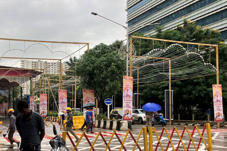 People walk past posters of India's Prime Minister Narendra Modi outside Jio World Convention Centre, the wedding venue of Anant Ambani, son of Indian billionaire Mukesh Ambani, in Mumbai, India, July 12, 2024.