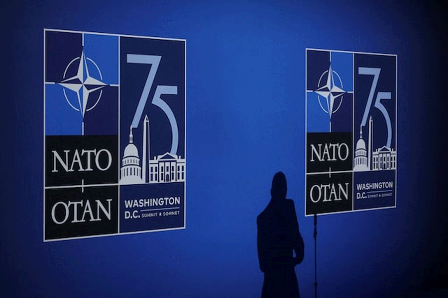 A journalist casts a shadow next to logos on the day of the NATO 75th Anniversary celebratory event in Washington, US, July 9, 2024.