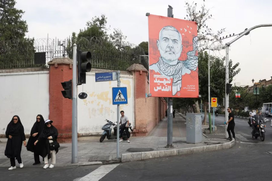 People walk past a banner with a picture of late Hamas leader Ismail Haniyeh in a street in Tehran, Iran, August 12, 2024.