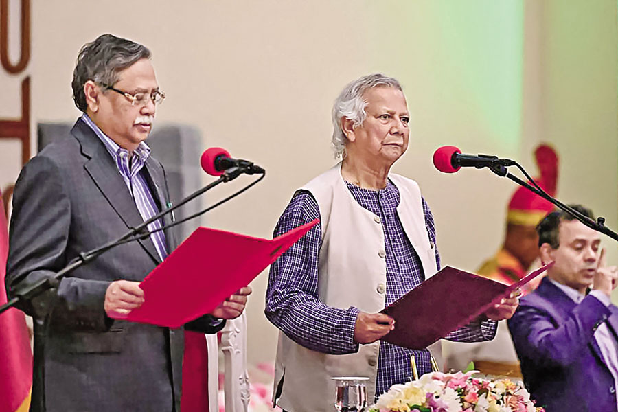 Muhammad Yunus (C) takes the oath of office as the chief adviser of Bangladesh's new interim government during the oath-taking ceremony administered by President Mohammed Shahabuddin (L) in Dhaka on August 8