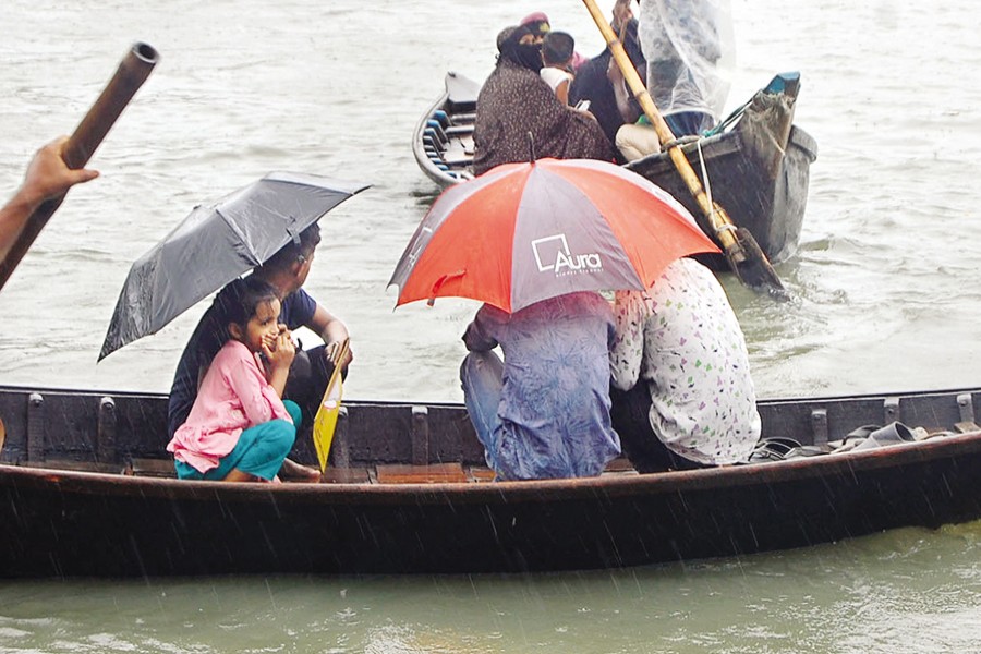 Passengers on boats in the Buriganga huddle under umbrellas in an attempt to protect them from rain that fell in Dhaka city on Saturday due to a low prevailing over the Bay of Bengal. — FE Photo