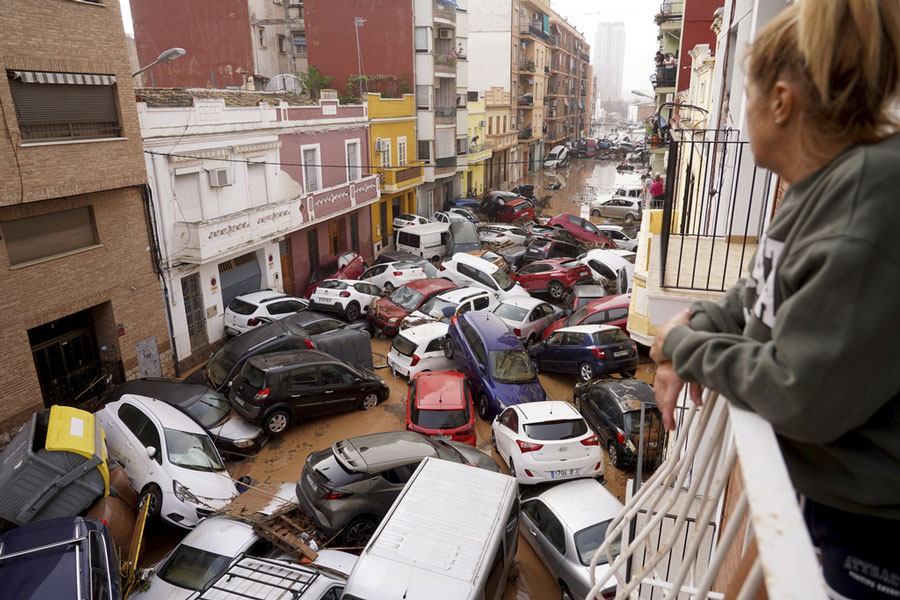 A woman looks out from her balcony as vehicles are trapped in the street during flooding in Valencia, Wednesday, Oct. 30, 2024.