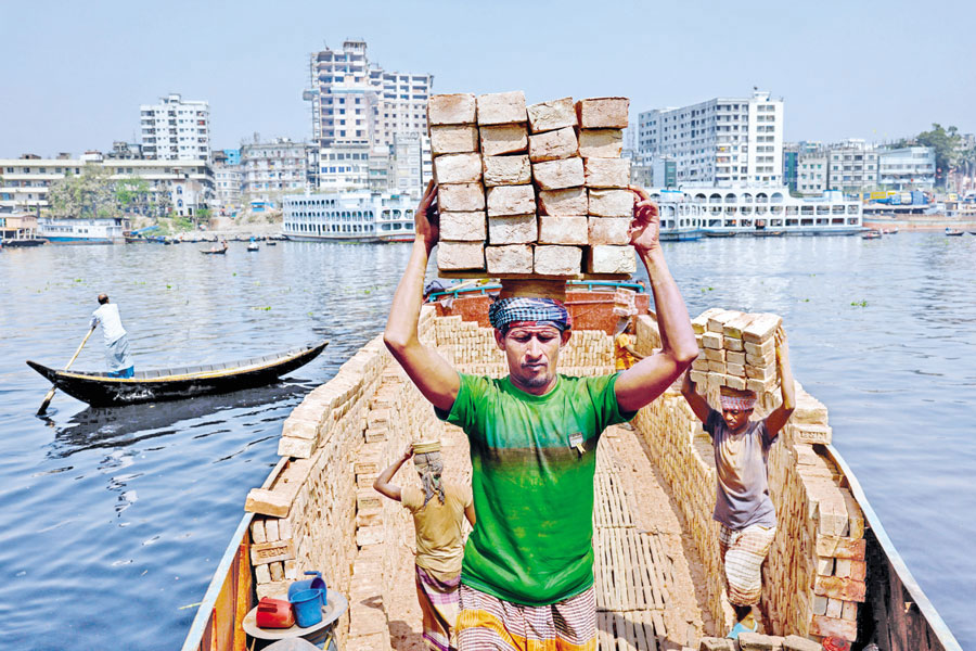 Labourers unload bricks from a trawler on the bank of the Buriganga river in Dhaka, Bangladesh, March 6, 2023